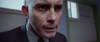 Movie still from “The Frighteners” (1996), directed by Peter Jackson – A person wearing a suit and tie; Extreme Close Up shot, Low angle
