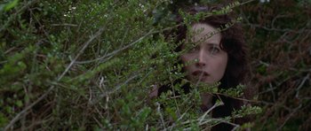 Movie still from “The Frighteners” (1996), directed by Peter Jackson – A woman hiding behind a bush looking at the camera; Close Up shot, Low angle