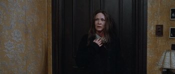 Movie still from “The Frighteners” (1996), directed by Peter Jackson – A woman standing in front of a wooden door; Medium shot, Over the shoulder angle