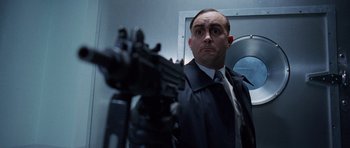 Movie still from “The Frighteners” (1996), directed by Peter Jackson – A man in a suit and tie holding a machine gun; Medium shot, Low angle