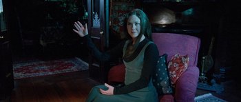Movie still from “The Frighteners” (1996), directed by Peter Jackson – A woman sitting on a chair in a living room; Medium shot, Over the shoulder angle