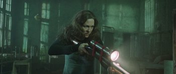 Movie still from “The Frighteners” (1996), directed by Peter Jackson – A woman is holding a flashlight in a room; Medium shot, Low angle