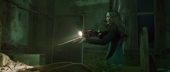 Movie still from “The Frighteners” (1996), directed by Peter Jackson – A woman is holding a flashlight in a dark room; Medium shot, Low angle