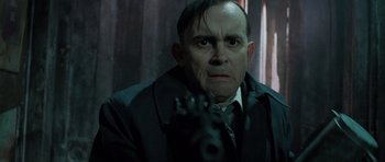 Movie still from “The Frighteners” (1996), directed by Peter Jackson – A man in a suit and tie holding a gun in front of him; Close Up shot, Low angle