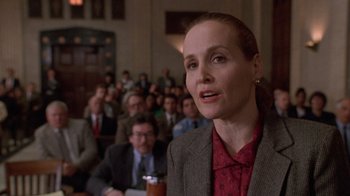 Movie still from “The Fugitive” (1993), directed by Andrew Davis – A woman in a red shirt is in front of an audience; Close Up shot, Low angle