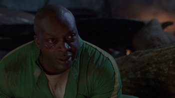 Movie still from “The Fugitive” (1993), directed by Andrew Davis – A man with a green shirt is sitting in a dark room; Close Up shot, High angle