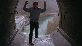 Movie still from “The Fugitive” (1993), directed by Andrew Davis – A man standing on the side of a river; Wide shot, High angle