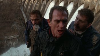 Movie still from “The Fugitive” (1993), directed by Andrew Davis – A group of men standing next to each other on a bridge; Medium shot, Low angle