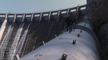 Movie still from “The Fugitive” (1993), directed by Andrew Davis – Two people are walking on the side of a dam; Extreme Wide shot, Low angle