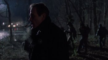 Movie still from “The Fugitive” (1993), directed by Andrew Davis – A man is smoking a cigarette in the dark; Medium shot, Over the shoulder angle