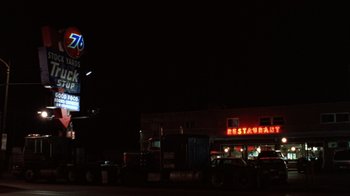 Movie still from “The Fugitive” (1993), directed by Andrew Davis – A restaurant sign lit up at night in the dark; Extreme Wide shot, Low angle