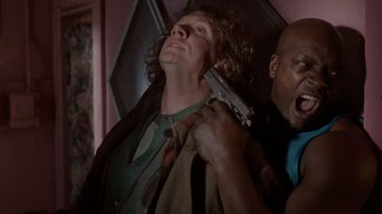 Movie still from “The Fugitive” (1993), directed by Andrew Davis – A man holding a gun up to his face; Medium shot, Low angle