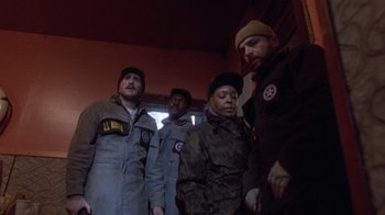 Movie still from “The Fugitive” (1993), directed by Andrew Davis – A group of men standing next to each other in a room; Medium shot, Low angle
