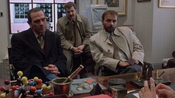Movie still from “The Fugitive” (1993), directed by Andrew Davis – A group of men sitting around a table; Medium shot, Over the shoulder angle