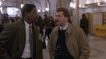 Movie still from “The Fugitive” (1993), directed by Andrew Davis – Two men are standing in a hallway talking; Medium shot, Low angle