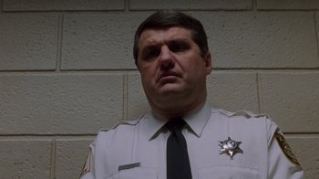 Movie still from “The Fugitive” (1993), directed by Andrew Davis – A man in a police officer's uniform looking to his left; Close Up shot, Low angle