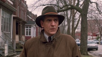 Movie still from “The Fugitive” (1993), directed by Andrew Davis – A man wearing a hat and a brown coat; Close Up shot, Low angle