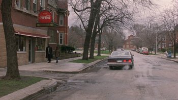Movie still from “The Fugitive” (1993), directed by Andrew Davis – A car parked on the side of the road near a building; Wide shot, High angle
