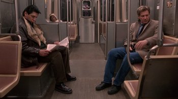 Movie still from “The Fugitive” (1993), directed by Andrew Davis – Three men are sitting on a subway train; Wide shot, High angle
