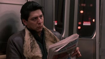 Movie still from “The Fugitive” (1993), directed by Andrew Davis – A man sitting on a train while reading a newspaper; Close Up shot, Over the shoulder angle