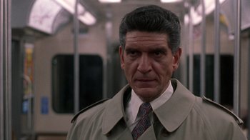 Movie still from “The Fugitive” (1993), directed by Andrew Davis – A person wearing a trench coat and a tie; Close Up shot, Low angle