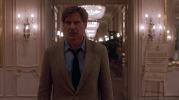 Movie still from “The Fugitive” (1993), directed by Andrew Davis – A man wearing a suit and tie in a hallway; Medium shot, Low angle