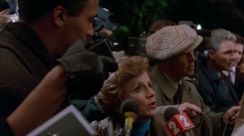 Movie still from “The Fugitive” (1993), directed by Andrew Davis – A group of people standing around a microphone; Close Up shot, Over the shoulder angle