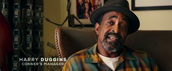 Movie still from “Popstar: Never Stop Never Stopping” (2016), directed by Akiva Schaffer – An older man wearing a plaid shirt and a hat; Close Up shot, Over the shoulder angle