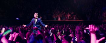 Movie still from “Popstar: Never Stop Never Stopping” (2016), directed by Akiva Schaffer – A man in a blue suit and a bow tie standing in front of a crowd; Wide shot, High angle