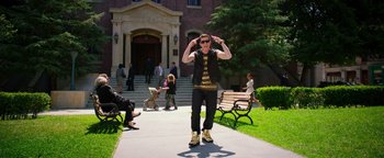 Movie still from “Popstar: Never Stop Never Stopping” (2016), directed by Akiva Schaffer – A man in a black shirt and black pants standing on a sidewalk; Wide shot, Over the shoulder angle