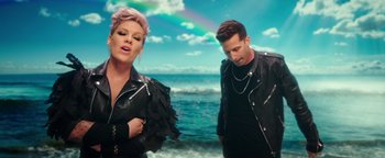 Movie still from “Popstar: Never Stop Never Stopping” (2016), directed by Akiva Schaffer – A man and a woman standing next to each other on the beach; Medium shot, High angle
