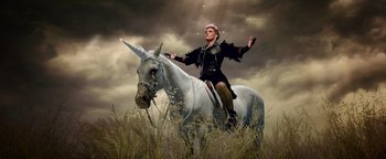 Movie still from “Popstar: Never Stop Never Stopping” (2016), directed by Akiva Schaffer – A woman riding a unicorn through a field of tall grass; Wide shot, Low angle