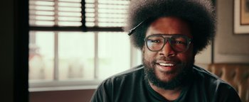 Movie still from “Popstar: Never Stop Never Stopping” (2016), directed by Akiva Schaffer – A person wearing glasses and a black shirt; Close Up shot, Over the shoulder angle