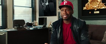 Movie still from “Popstar: Never Stop Never Stopping” (2016), directed by Akiva Schaffer – A person sitting in a chair wearing a hat; Medium shot, Over the shoulder angle