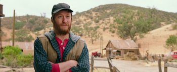 Movie still from “Popstar: Never Stop Never Stopping” (2016), directed by Akiva Schaffer – A man standing in front of a barn with his arms crossed; Close Up shot, Over the shoulder angle