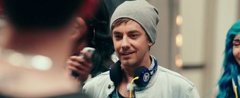 Movie still from “Popstar: Never Stop Never Stopping” (2016), directed by Akiva Schaffer – A person wearing headphones and a hat; Close Up shot, Over the shoulder angle