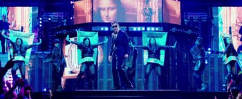 Movie still from “Popstar: Never Stop Never Stopping” (2016), directed by Akiva Schaffer – A man in a suit and sunglasses on a stage; Wide shot, Low angle