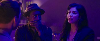 Movie still from “Popstar: Never Stop Never Stopping” (2016), directed by Akiva Schaffer – A man and a woman sitting next to each other in front of purple lights; Close Up shot, Over the shoulder angle