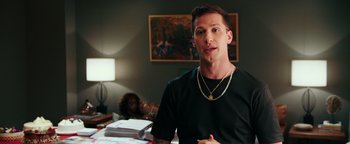 Movie still from “Popstar: Never Stop Never Stopping” (2016), directed by Akiva Schaffer – A man in a black shirt is sitting at a table; Medium shot, Over the shoulder angle