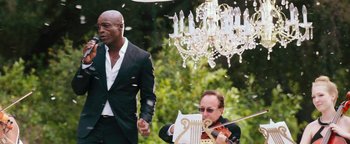 Movie still from “Popstar: Never Stop Never Stopping” (2016), directed by Akiva Schaffer – A man in a suit playing a violin while another man in a black suit looks on; Medium shot, Low angle