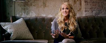 Movie still from “Popstar: Never Stop Never Stopping” (2016), directed by Akiva Schaffer – A woman sitting on top of a couch with her hands up; Close Up shot, Over the shoulder angle