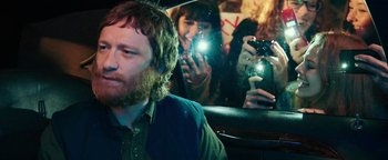 Movie still from “Popstar: Never Stop Never Stopping” (2016), directed by Akiva Schaffer – A group of people taking pictures in a car; Close Up shot, Over the shoulder angle