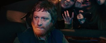 Movie still from “Popstar: Never Stop Never Stopping” (2016), directed by Akiva Schaffer – A man with a beard and a woman with a phone in his hand; Close Up shot, Over the shoulder angle