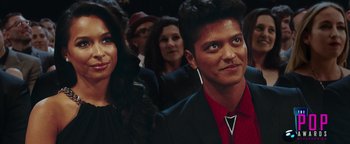 Movie still from “Popstar: Never Stop Never Stopping” (2016), directed by Akiva Schaffer – A man and a woman are standing in front of a group of people; Close Up shot, Overhead angle