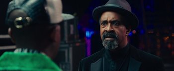 Movie still from “Popstar: Never Stop Never Stopping” (2016), directed by Akiva Schaffer – A man with a beard wearing a black suit and a hat; Close Up shot, Over the shoulder angle