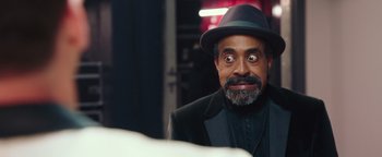 Movie still from “Popstar: Never Stop Never Stopping” (2016), directed by Akiva Schaffer – A man in a black suit and a black hat; Close Up shot, Over the shoulder angle