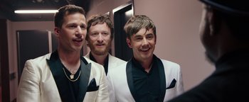 Movie still from “Popstar: Never Stop Never Stopping” (2016), directed by Akiva Schaffer – A group of men in suits posing for a picture; Medium shot, Over the shoulder angle