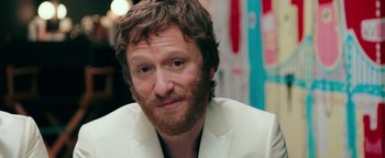 Movie still from “Popstar: Never Stop Never Stopping” (2016), directed by Akiva Schaffer – A person wearing a suit and beard; Close Up shot, Over the shoulder angle