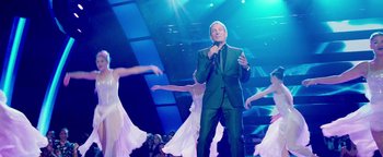 Movie still from “Popstar: Never Stop Never Stopping” (2016), directed by Akiva Schaffer – A man in a green suit is holding a microphone; Wide shot, Low angle