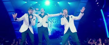 Movie still from “Popstar: Never Stop Never Stopping” (2016), directed by Akiva Schaffer – A group of men singing on a stage; Wide shot, Low angle